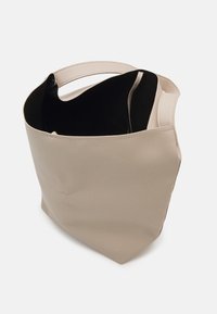 Béžová kožená taška na rameno s texturovaným povrchem, otevřeným horním dílem a krátkými uchy. Vnitřek je vyložený černou látkou, což vytváří kontrast.