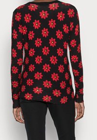 Schwarzer Pullover mit langen Ärmeln, der ein florales Muster aus roten Blumen mit gelben Zentren aufweist. Weicher Stoff, schmaler Schnitt und gerippte Bündchen.
