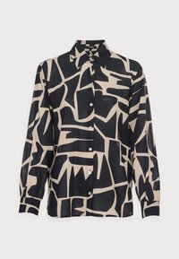 Camicia a maniche lunghe con bottoni, caratterizzata da un motivo geometrico astratto in nero e beige, con colletto a punta, su sfondo bianco.