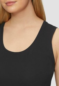 Zwarte tanktop met een ronde halslijn en brede schouderbanden. Gemaakt van een soepele, rekbare stof, heeft het een aansluitende pasvorm en minimale stiksel details.