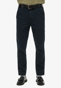 Donkerblauwe katoenen broek met een slim fit, voorzien van zijzakken, een riem met een metalen gesp en boorden bij de enkel.