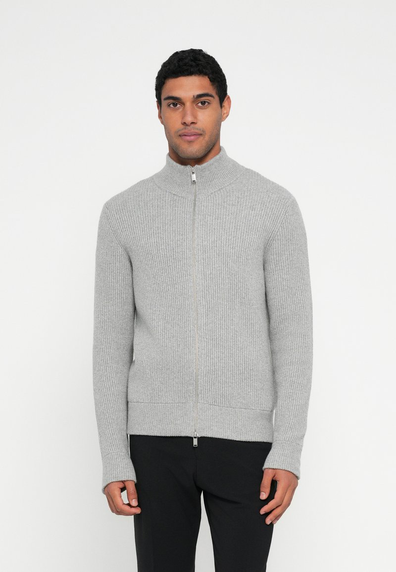 Camisola de malha cinzenta com fecho de correr, gola alta e mangas compridas, apresentando uma textura suave e detalhes subtis na bainha.