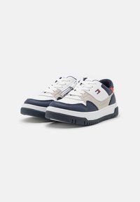 Witte en marineblauwe sneakers met een gladlederen bovenwerk, ronde neus, witte veters en een gestructureerde rubbersole; voorzien van een rode en blauwe accent.