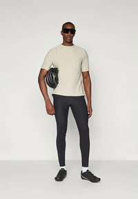 T-shirt de manga curta cinza claro, leggings pretas, capacete de ciclismo preto e óculos de sol; apresenta um design ajustado e texturas suaves.