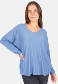 Lässiges, langärmeliges Oberteil in Hellblau mit einem weiten V-Ausschnitt und weichem Material. Das Kleidungsstück hat eine entspannte Silhouette und liegt sanft an.