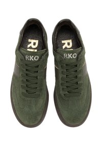 Tummanvihreät mokkanahka-sneakerit, joissa on musta nahkasuikale sivussa, pyöreä kärki ja kullanvärinen logoyksityiskohta kielessä.