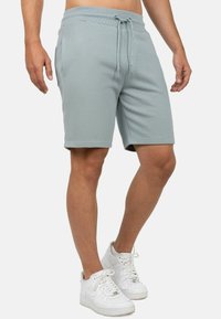 Lichtblauwe katoenmix shorts met een elastische tailleband en koord. Zijzakken en een soepele textuur. Gepaard met witte sneakers.