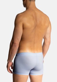 Helle blaue Herren-Badeshorts mit einer glatten Textur und einem elastischen Bund, von hinten betrachtet, die ein körperbetontes Design zeigen.