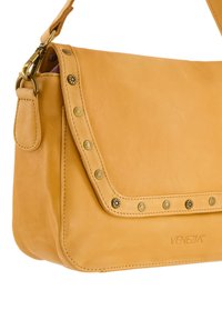 Tan læder crossbody taske med klaplukning, nitter langs kanten og et logo præget på forsiden. Justerbar rem medfølger.