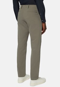 Khaki kalhoty vyrobené z hladké látky, s kapsami na zadní straně, slim fit a zkombinované s bílými teniskami.