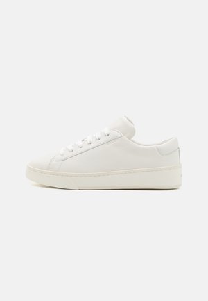 Vit sneakers i läder med låg profil, rund tå och flat gummisula. Har platta skosnören och minimala sömmar.