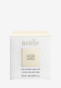 Vitt texturerat förpackning med präglat mönster, guldiga detaljer och ett krämfärgat lock. Etiketten säger "HSR LIFTING," vilket indikerar en anti-wrinkle kräm.