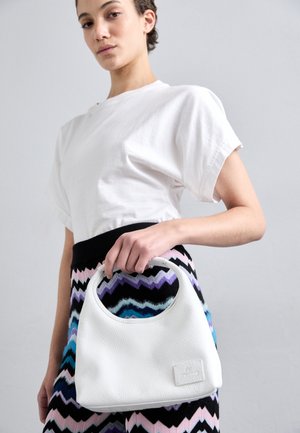 Sac à main en cuir blanc avec une poignée courbée, présentant une surface texturée et un patch logo rectangulaire, assorti à une jupe multicolore à motifs.