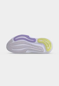 Semelle d'une chaussure de sport blanche avec des zones de gomme violettes et jaunes sur un fond gris uni.