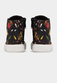 Μαύρα ψηλά αθλητικά παπούτσια με λευκές σόλες, διακοσμημένα με πολύχρωμα σχέδια πίτσας και καυτερής πιπεριάς, που εμφανίζονται από πίσω με πλευρικά φερμουάρ.