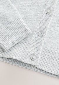 Cardigan en maille gris clair avec poignets, ourlet et patte de boutonnage à côtes, présentant trois boutons ronds visibles.