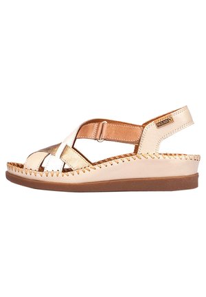 Sandalia de cuero beige y dorado con correas cruzadas, correa de tobillo ajustable y suela texturizada. Detalles cosidos a mano alrededor de los bordes.