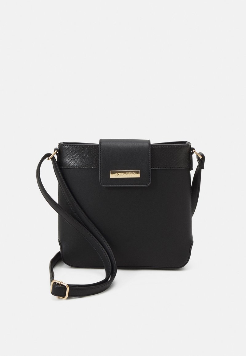 Borsa a tracolla nera in pelle con una superficie liscia, forma rettangolare, chiusura a patta magnetica e dettagli metallici color oro.