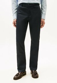 Marinebukser lavet af bomuldsblanding, med et lige ben design, knap- og lynlåslukning samt standardlommer. Brune loafers fuldender looket.