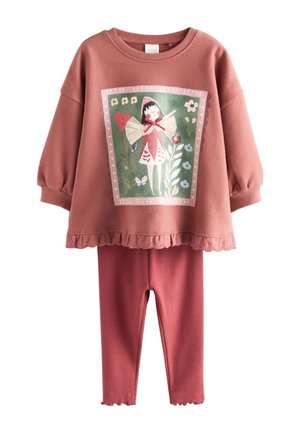 Dwuczęściowy strój dziecięcy w kolorze przybrudzonego różu, z bluzką z długim rękawem i falbaną u dołu oraz ilustracją wróżki, w zestawieniu z prążkowanymi legginsami.
