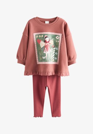 Vaikiškas dviejų dalių komplektas dulkiškai rožinės spalvos: ilgomis rankovėmis palaidinė su raukiniais apačioje ir fėjos iliustracija, derinamas su gofruotomis tamprėmis.