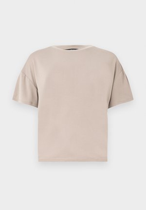 Camiseta de algodón beige de manga corta, de gran tamaño, con cuello redondo y dobladillo recto sobre un fondo claro liso.