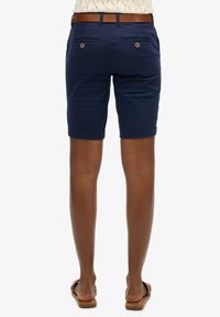 Pantaloni corti blu navy realizzati in tessuto leggero, con una vestibilità su misura, orli arrotolati e due tasche posteriori con chiusure a bottone.