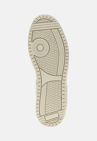 Suola della scarpa realizzata in un materiale di gomma crema testurizzato, caratterizzato da un motivo circolare, righe ondulate e un piccolo accento rettangolare.