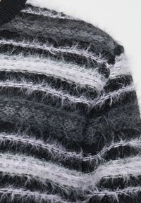 Close-up of black and gray knitted fabric with fuzzy texture and horizontal stripes in varying shades of gray and black.