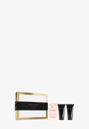 Set de regalo de perfume con caja dorada, botella transparente con tapa rosa etiquetada "narciso rodriguez for her," y dos tubos de loción negra.
