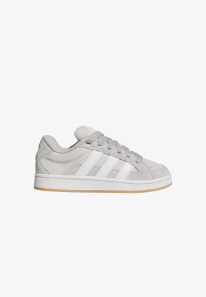Jasnoszare zamszowe sneakersy z trzema białymi paskami po boku, szarymi sznurowadłami i białą podeszwą z brązowym spodem.