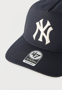 Ρουά μπλε ρυθμιζόμενο καπέλο μπέιζμπολ με κεντητό λογότυπο "NY" σε λευκό χρώμα και αυτοκόλλητο της μάρκας '47 Hitch στην άκρη.