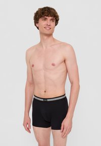 Svarta boxershorts med en grårandig midjeresår, tillverkade i ett mjukt tyg, med en åtsittande design och sydda detaljer.