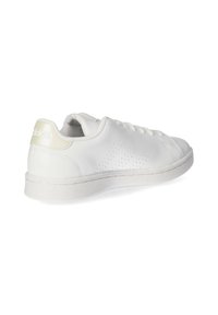 Basket blanche en matériau synthétique lisse, avec des détails perforés sur les côtés, semelle blanche plate et accents beiges au niveau du talon.