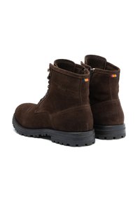 Stivaletti in suede marrone con lacci frontali, targhette rettangolari e suole in gomma nera con grip testurizzato.