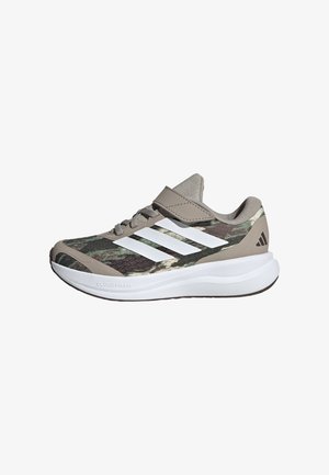 Dziecięce trampki Adidas w wzór kamuflażu, z białymi paskami, szarymi akcentami, paskiem na rzep oraz grubą białą, wyściełaną podeszwą.