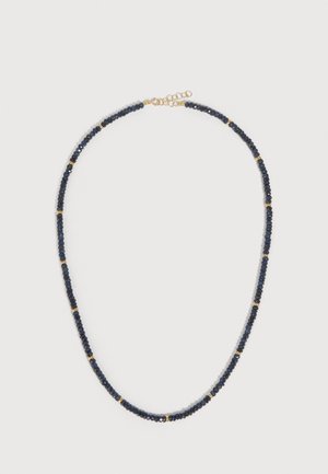 Collier avec petites perles facettées bleu foncé et petites perles intercalaires dorées, fermoir doré avec chaîne réglable, posé à plat sur fond blanc.