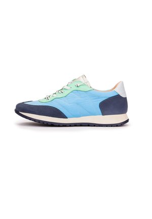 Zapatilla baja con tejido acolchado azul claro, superposiciones de ante azul marino, detalles en verde menta, cordones blancos y suela crema sobre fondo blanco.