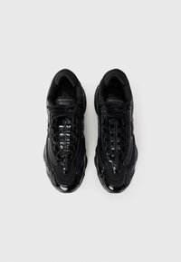 Black athletic sneakers featuring a textured upper, shiny accents, laces, and a rounded sole. Designed for comfort and support.