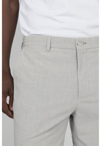 Pantalones cortos de color gris claro con un tejido texturizado, frente plano, bolsillos laterales y cierre de un solo botón.
