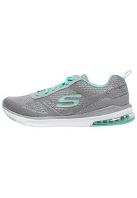 Chaussure de sport grise avec une tige en mesh texturé, des accents turquoise, un système de laçage et une semelle blanche rembourrée avec amortissement à air.