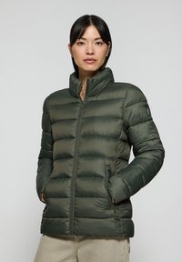 Grön puffjacka med hög krage, dragkedja fram och kviltad design. Tillverkad av ett slätt, glänsande tyg med sidfickor.