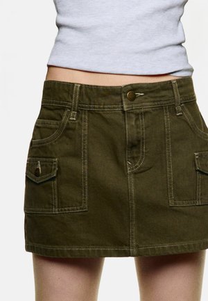 Olive green denim skirt with front pockets, stitched detailing, and a button closure at the waist. Hem ends above the knee.