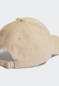 Gorra de algodón beige con visera curvada, correa ajustable, tela texturizada y ojales de ventilación en los laterales.