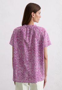 Kurzarmoberteil in Pink mit weißem abstraktem Muster, mit gerafftem Rücken-Halsausschnitt und lockerer Passform, aus leichtem Stoff gefertigt.