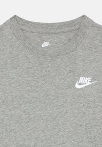 Siva Nike majica s okruglim izrezom i bijelim vezenim Nike logotipom na prsima te tiskanim logotipom unutar izreza vrata.