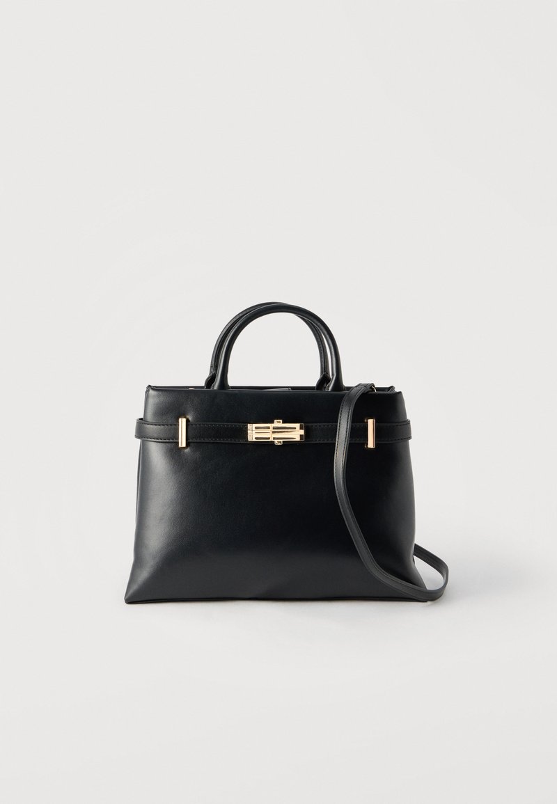 Črna usnjena torbica z dvema ročajema, zlato pravokotno zaponko in odstranljivim naramnim trakom na belem ozadju.
