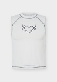 Λευκό αμάνικο τοπ με γκρι φυλετικό σχέδιο καρδιάς στο κέντρο του στήθους και ορατές γκρι ραφές κατά μήκος της λαιμόκοψης, των μασχάλων και του τελειώματος.