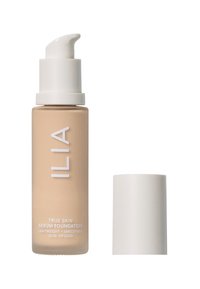 ILIA True Skin Serum Foundation i en glasflaska med beige nyans, vit texturerad pump och matchande lock. Har tydlig etiketttext.