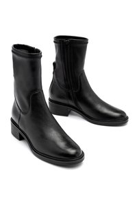 Bottes basses en cuir noir à texture lisse, fermeture éclair et talon bloc. Présentent un design élégant et un bout arrondi.